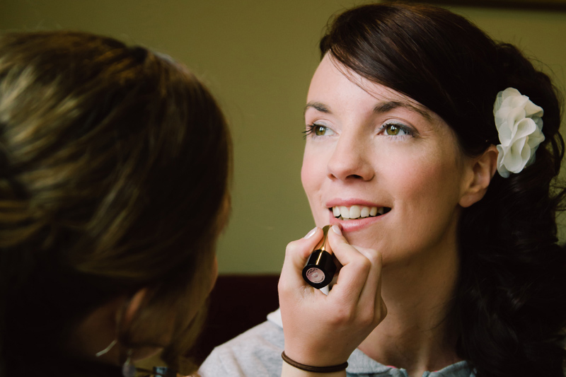 Bride having her lipstick applied by the makeup artist