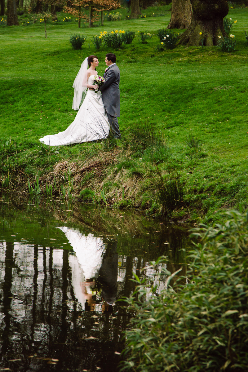 The Bride and Groom chat in a field of daffodils by a lake